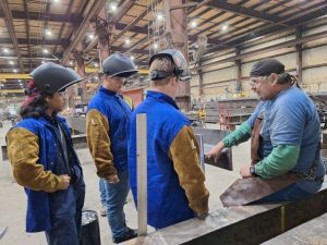 Welding supervisor giving instructions to a group of new trainees or employees.